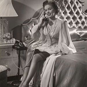Woman in lingerie on phone in bedroom