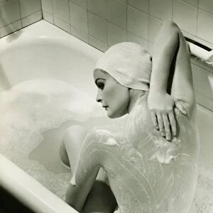 Woman washing herself in bathtub, (B&W), elevated view