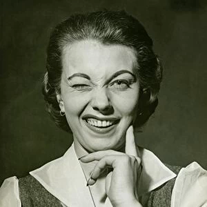 Woman winking in studio, (B&W), portrait