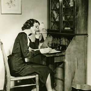 Woman writing letter at bureau, (B&W)