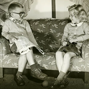 Young boy and girl sitting on sofa, imitating married couple
