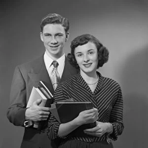 Young man and woman holding books, portrait