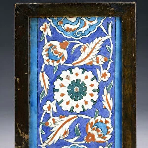 An Iznik border tile, with a central flowerhead between scrolling palmette and leafy vine