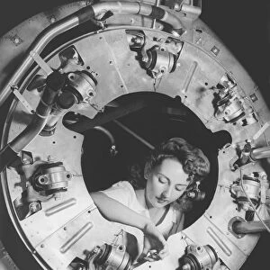 A woman assembles part of the cowling of a B-25 bomber motor. circa 1942
