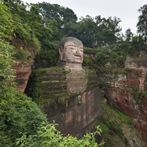 Leshan Giant Buddha, the largest and tallest stone Buddha statue in the world, carved into the rock face on the red, sandstone cliffs overlooking the confluence of the Min River and Dadu River; Sichuan Province, China