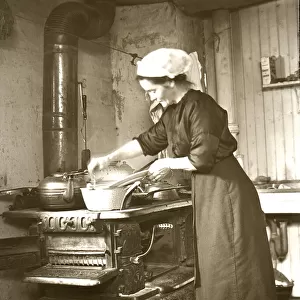 Woman cooking on a range at home in America around 1900; United States of America