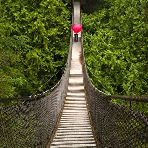 Woman With A Red Heart-Shaped Umbrella Crossing The Lynn Canyon Suspension Bridge, North Vancouver; Vancouver, British Columbia, Canada