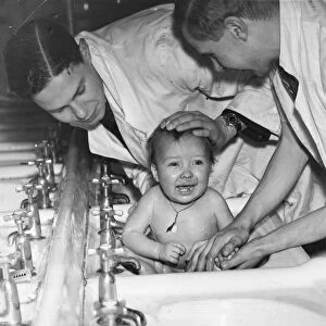 A baby gets a bath in the sink. Picture taken 4th January 1941