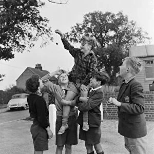 A group of friends taking part in a game of conkers outside their house
