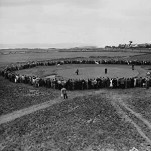 Henry Cotton, watched by a large crowd, holing out at the 16th hole during the 1956 Open