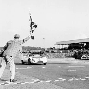 Jim Clark takes the checkered flag in his Lotus 23 to win the Martini Rossi Trophy race