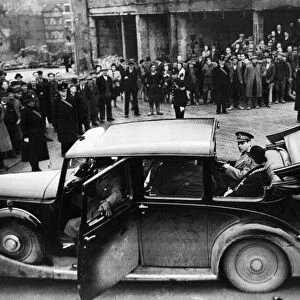 King George VI sits in the back of an open top car as he visits the bomb damaged city of