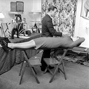 Magician Bernard Hughes: Performing a levitation trick on his female assistant