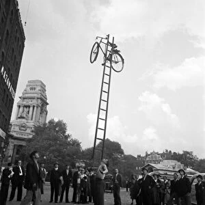 A street entertainer at Tower Hill, London balancing a bicycle on a ladder using his chin