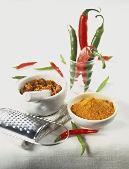 Curcuma longa, ground Turmeric in small ceramic bowl, ground spices in pestle and mortar, metal grater, fresh green and red Chilli Peppers in jar Curcuma longa, ground Turmeric in small ceramic bowl, ground spices in pestle and mortar, metal grater, fresh green and red Chilli Peppers in jar